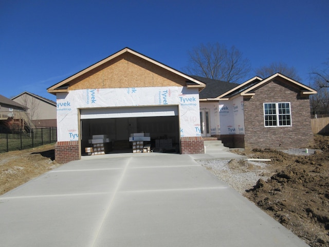 view of front of house with concrete driveway, an attached garage, fence, and stucco siding