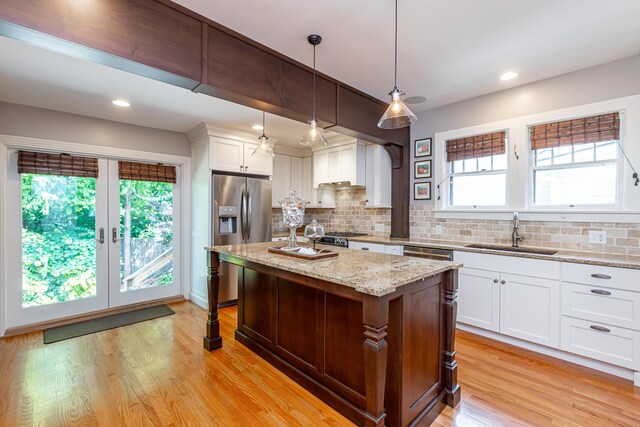 kitchen with light hardwood / wood-style flooring, sink, decorative light fixtures, decorative backsplash, and stainless steel fridge with ice dispenser