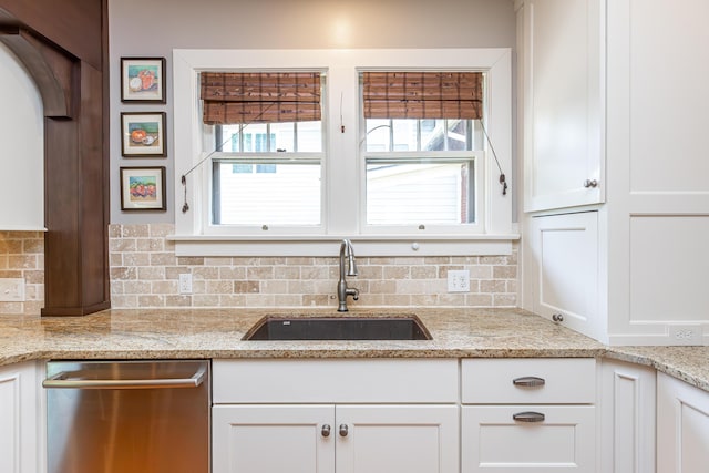kitchen featuring a sink, tasteful backsplash, stainless steel dishwasher, and white cabinetry
