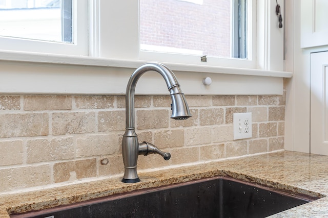 details featuring decorative backsplash, a sink, and light stone countertops