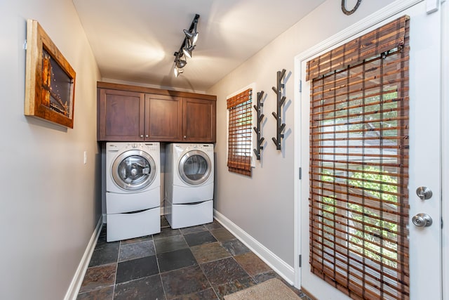 laundry room featuring baseboards, stone tile floors, cabinet space, and washer and dryer
