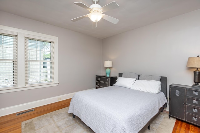 bedroom featuring ceiling fan, baseboards, visible vents, and wood finished floors