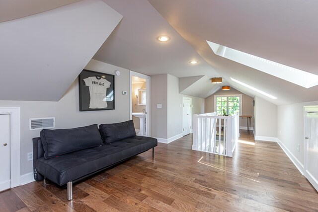 interior space featuring hardwood / wood-style flooring and vaulted ceiling with skylight