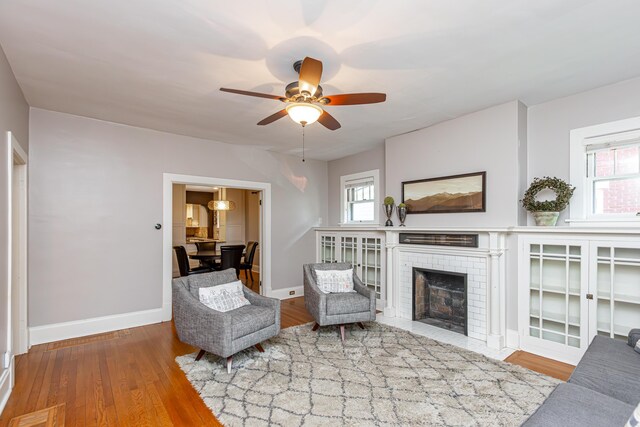 living room featuring hardwood / wood-style floors, ceiling fan, a brick fireplace, and a wealth of natural light