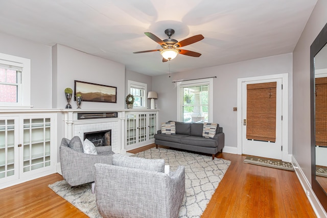 living room with baseboards, ceiling fan, wood finished floors, and a fireplace