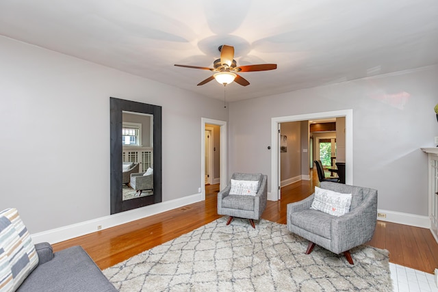 sitting room with a ceiling fan, baseboards, and wood finished floors