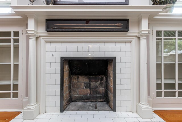 room details featuring a fireplace, crown molding, decorative columns, and hardwood / wood-style flooring