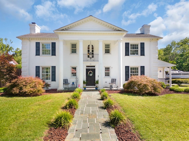 neoclassical home with a balcony and a front yard