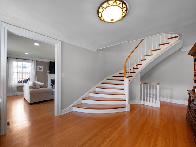 stairway featuring crown molding and wood-type flooring