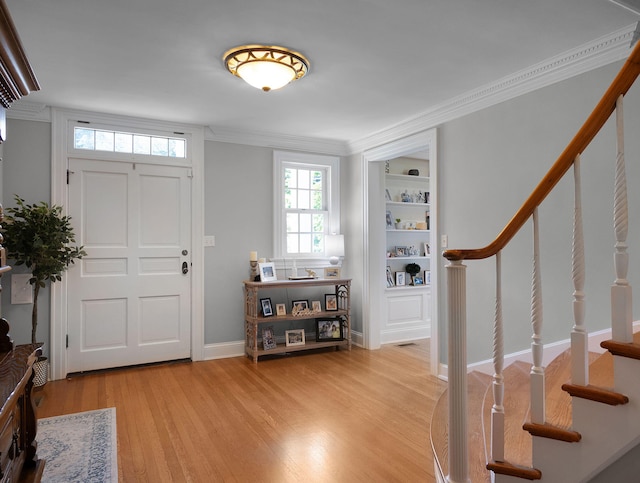 entrance foyer with ornamental molding and light hardwood / wood-style flooring