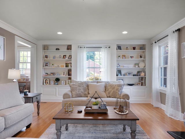 living room featuring light wood-type flooring, crown molding, and built in shelves