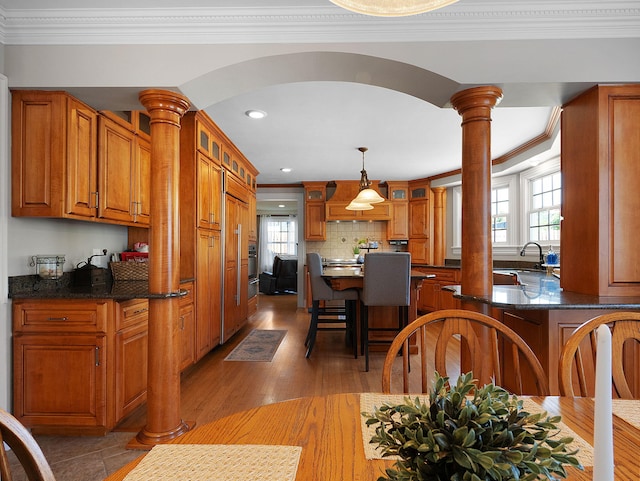 dining room featuring sink, crown molding, dark hardwood / wood-style flooring, and ornate columns