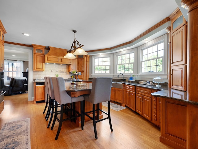 dining area featuring sink, light wood-type flooring, and crown molding