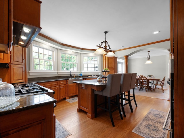 kitchen with decorative columns, a wealth of natural light, a kitchen breakfast bar, and a center island