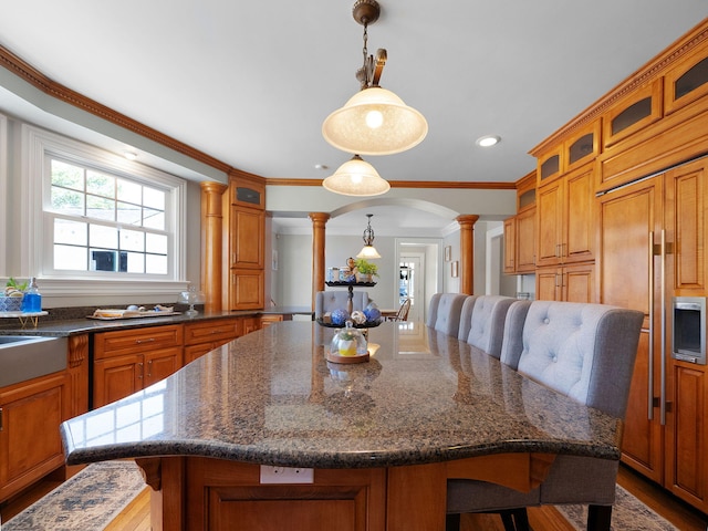 kitchen featuring a breakfast bar, decorative columns, a kitchen island, and hanging light fixtures