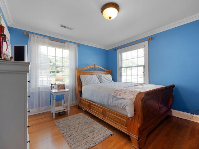 bedroom featuring multiple windows, light hardwood / wood-style floors, and crown molding