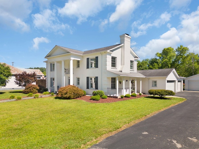 view of front of house featuring covered porch, a front lawn, and a garage