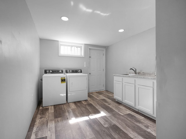 laundry area with hardwood / wood-style flooring, washing machine and dryer, cabinets, and sink