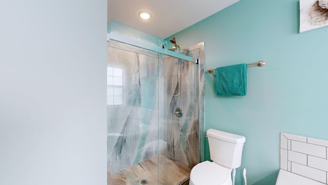 bathroom featuring toilet and a shower with shower door