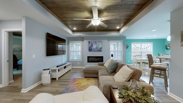 living room with crown molding, wood ceiling, a raised ceiling, light hardwood / wood-style flooring, and ceiling fan