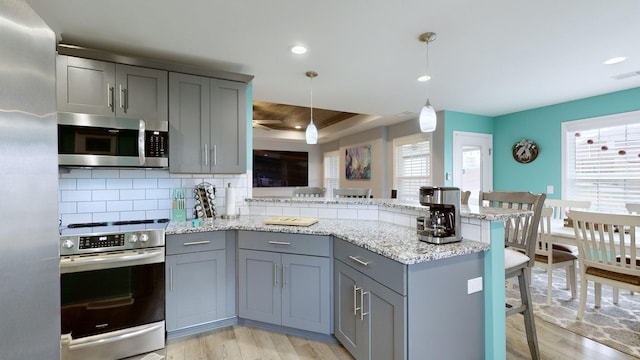 kitchen featuring decorative light fixtures, stainless steel appliances, tasteful backsplash, kitchen peninsula, and a breakfast bar