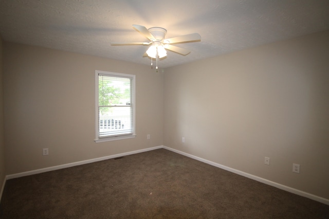 spare room with dark carpet and ceiling fan