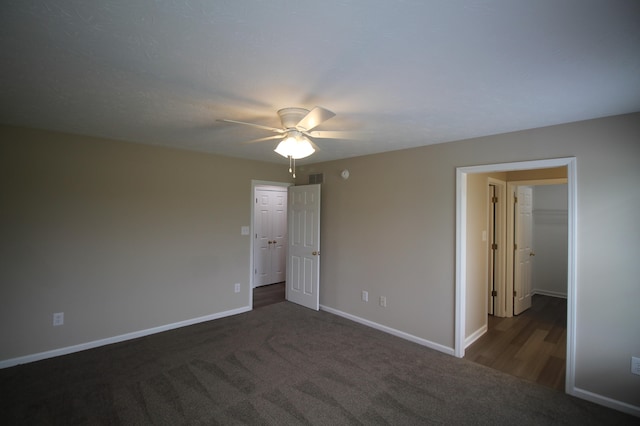 unfurnished bedroom with dark colored carpet, a closet, and ceiling fan