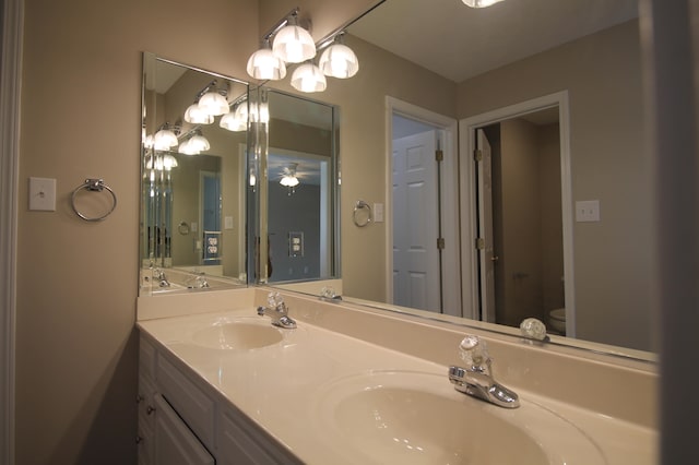 bathroom with toilet, ceiling fan, and double vanity