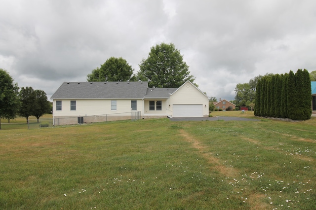 rear view of property featuring a garage and a lawn