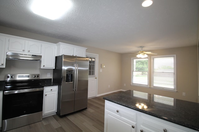 kitchen featuring appliances with stainless steel finishes, white cabinets, dark stone countertops, dark wood-type flooring, and ceiling fan