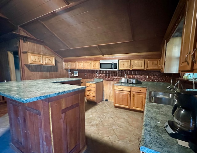 kitchen featuring vaulted ceiling, sink, wood walls, and a center island