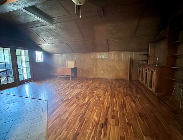 additional living space featuring ceiling fan, lofted ceiling, wood-type flooring, and wooden walls