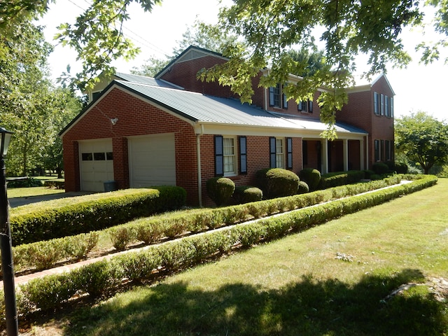 cape cod home featuring a garage and a front lawn