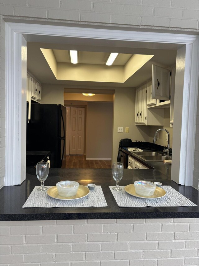 kitchen with carpet flooring, white cabinets, black appliances, a raised ceiling, and crown molding