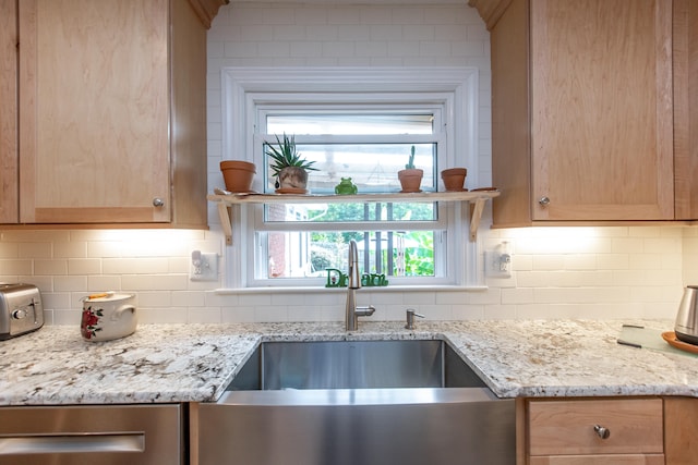 kitchen featuring light brown cabinetry, sink, tasteful backsplash, and light stone counters