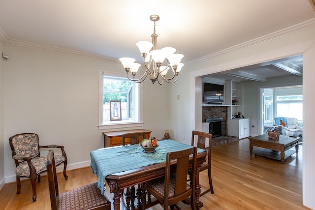 dining area with a fireplace, a chandelier, crown molding, and light hardwood / wood-style floors