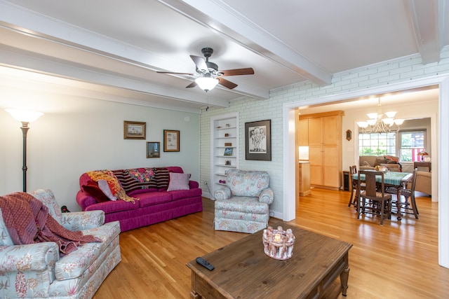 living room with ceiling fan with notable chandelier, beamed ceiling, brick wall, ornamental molding, and light hardwood / wood-style flooring