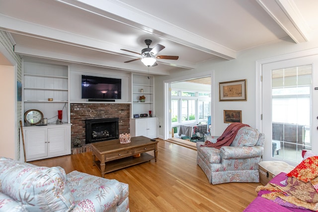 living room with light hardwood / wood-style floors, beam ceiling, and a brick fireplace