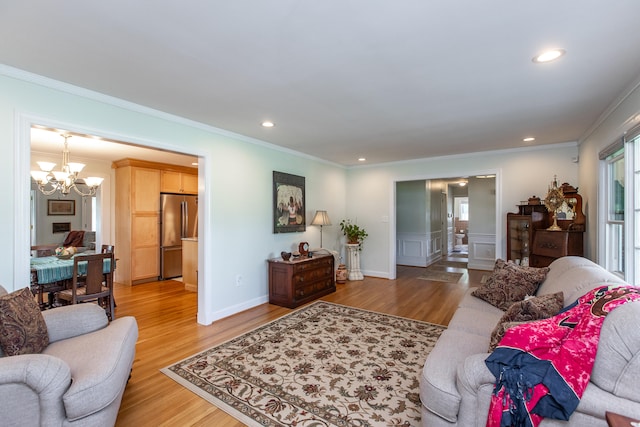 living room with light hardwood / wood-style floors, ornamental molding, and an inviting chandelier