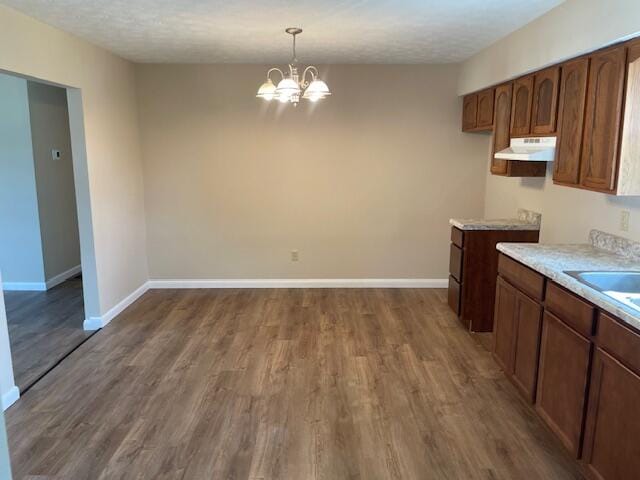 kitchen featuring hardwood / wood-style flooring, an inviting chandelier, and a textured ceiling