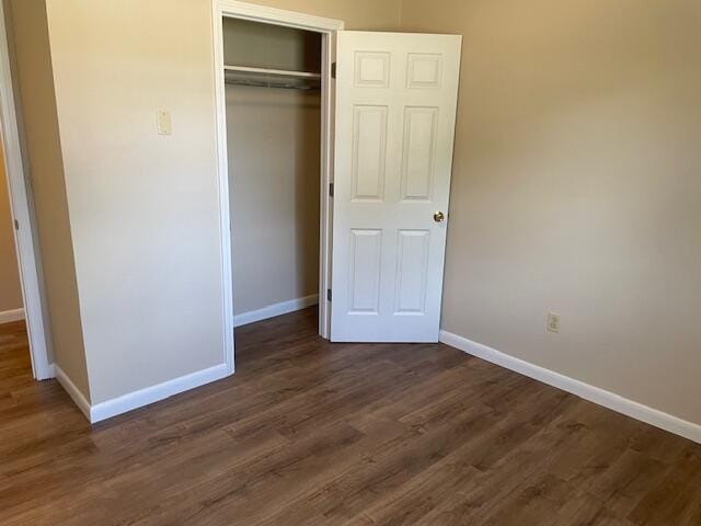 unfurnished bedroom with a closet and dark hardwood / wood-style flooring