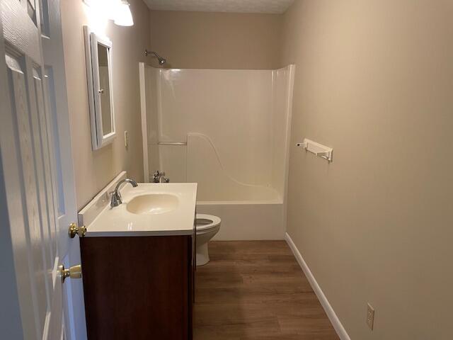 full bathroom featuring vanity, toilet, hardwood / wood-style floors, and tub / shower combination