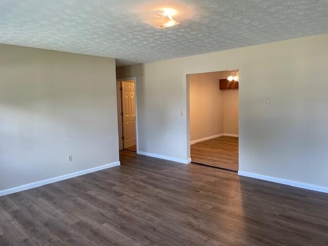 empty room with a textured ceiling and dark hardwood / wood-style floors