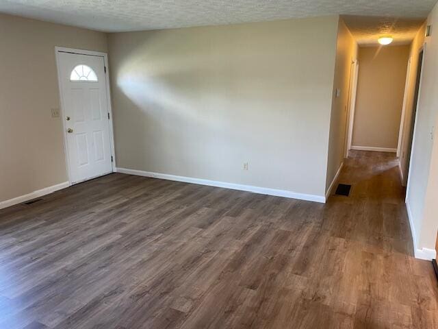 foyer entrance with dark hardwood / wood-style floors and a textured ceiling