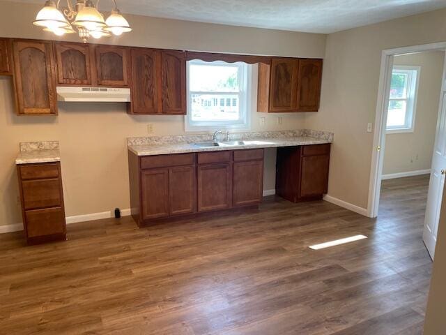 kitchen with decorative light fixtures, a notable chandelier, sink, dark wood-type flooring, and a textured ceiling