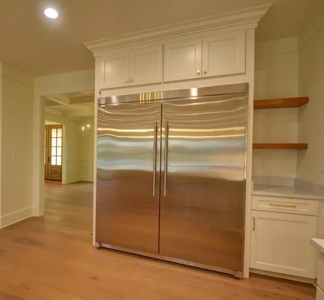 kitchen featuring white cabinetry, coffered ceiling, stainless steel built in fridge, and light wood-type flooring