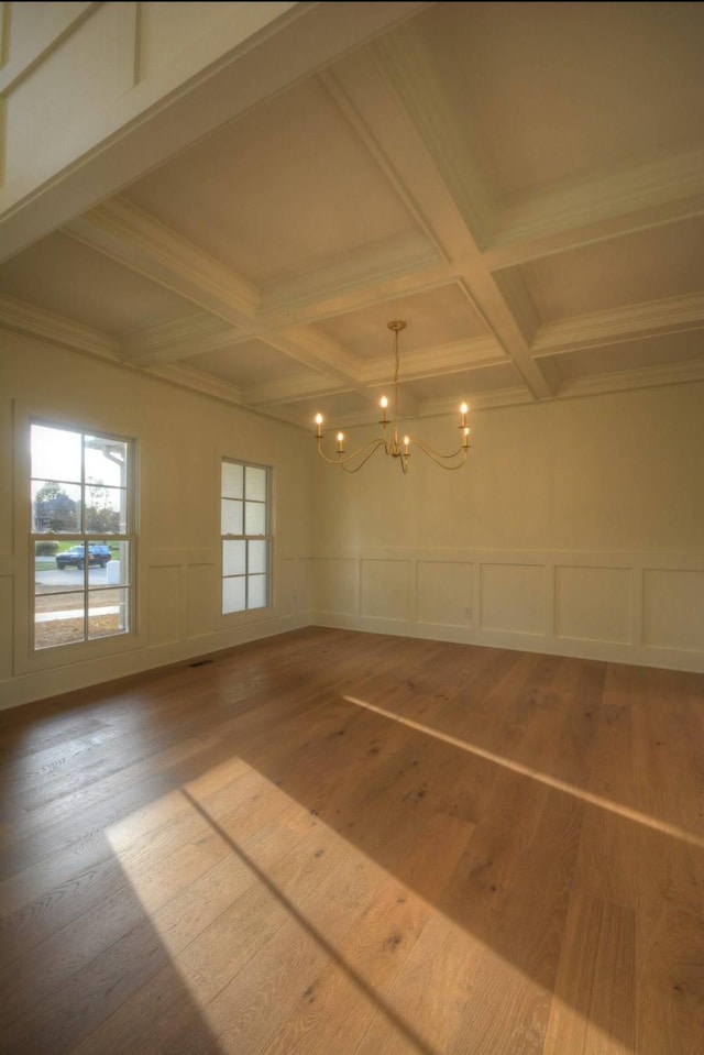 spare room with wood-type flooring, coffered ceiling, beam ceiling, and a notable chandelier