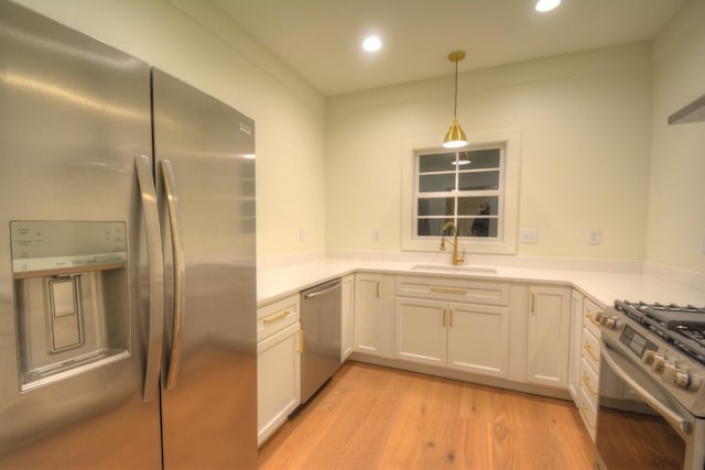 kitchen with appliances with stainless steel finishes, sink, hanging light fixtures, and white cabinets