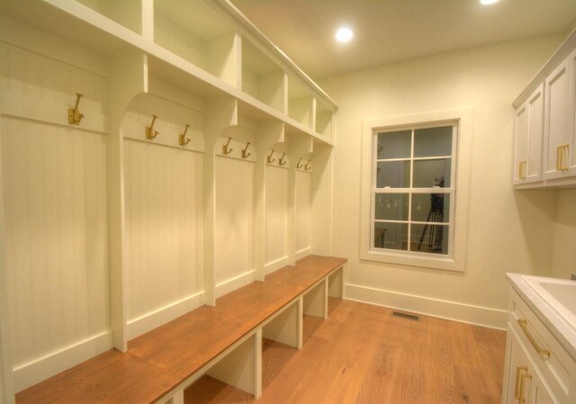 laundry area with cabinets, washer hookup, sink, and light wood-type flooring