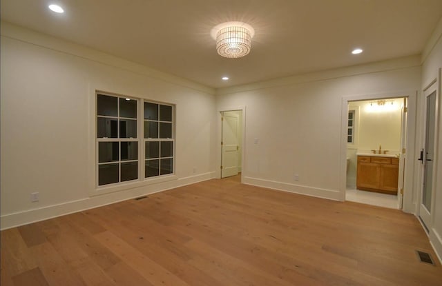 unfurnished bedroom featuring sink, ornamental molding, connected bathroom, and light hardwood / wood-style floors